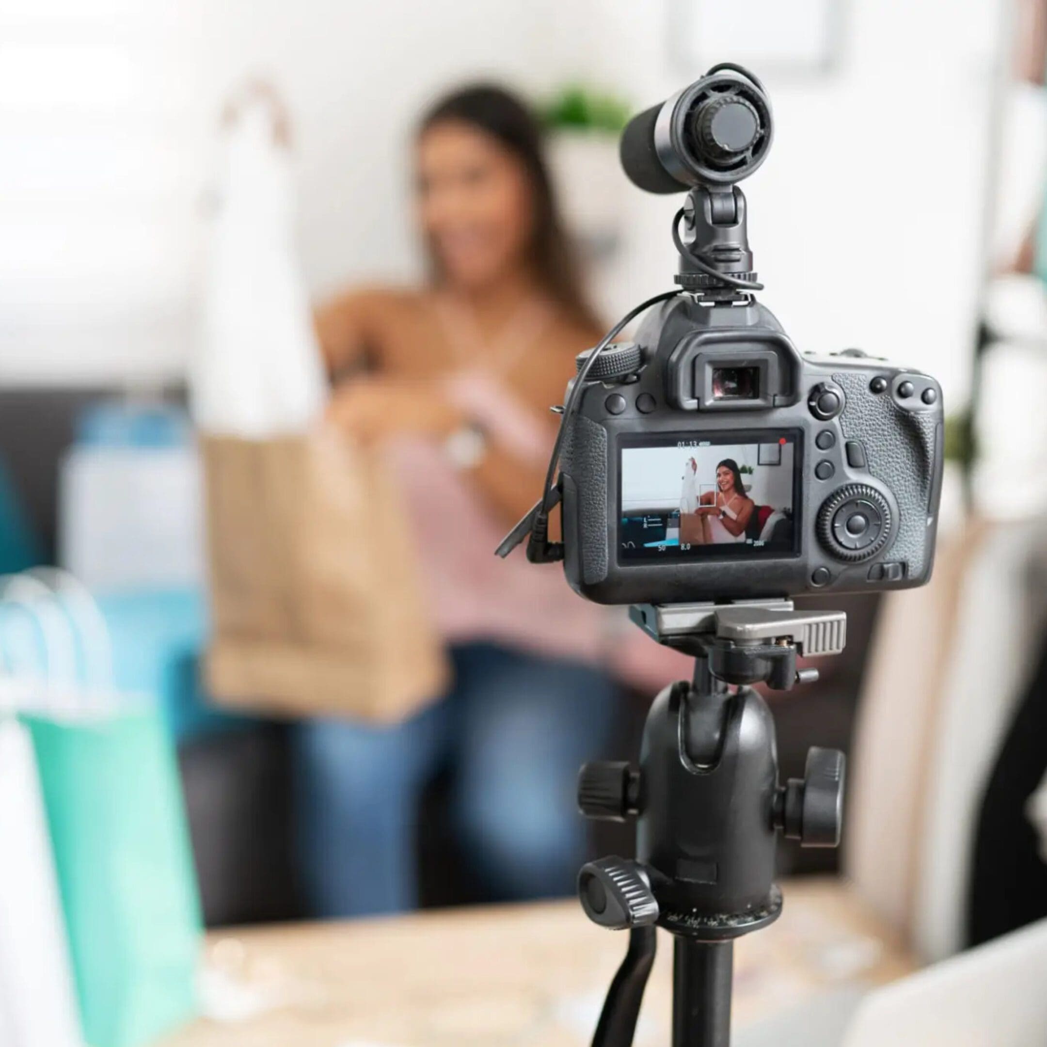 A camera on a tripod recording a woman holding a shopping bag.