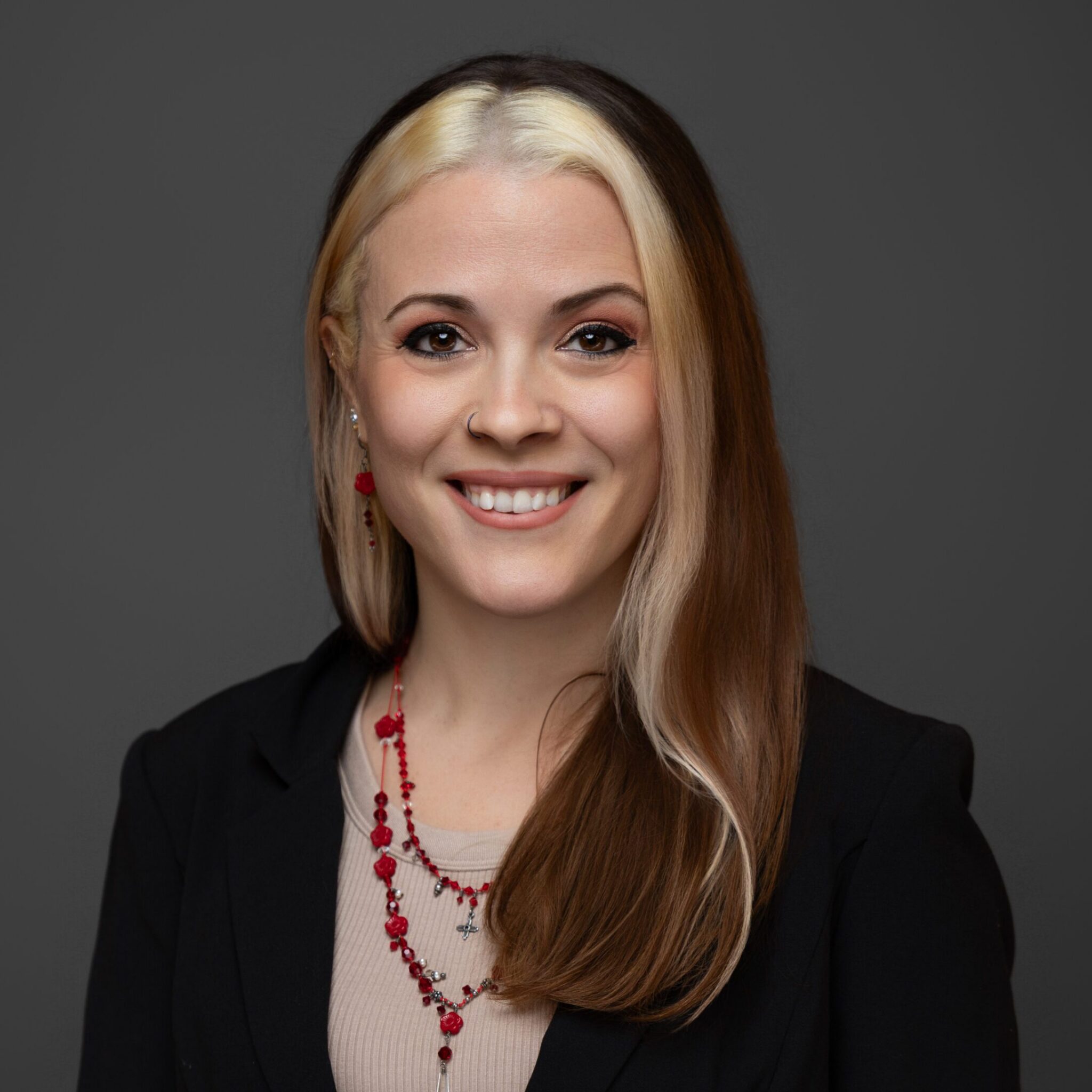Professional woman with blonde hair smiling against a gray background.