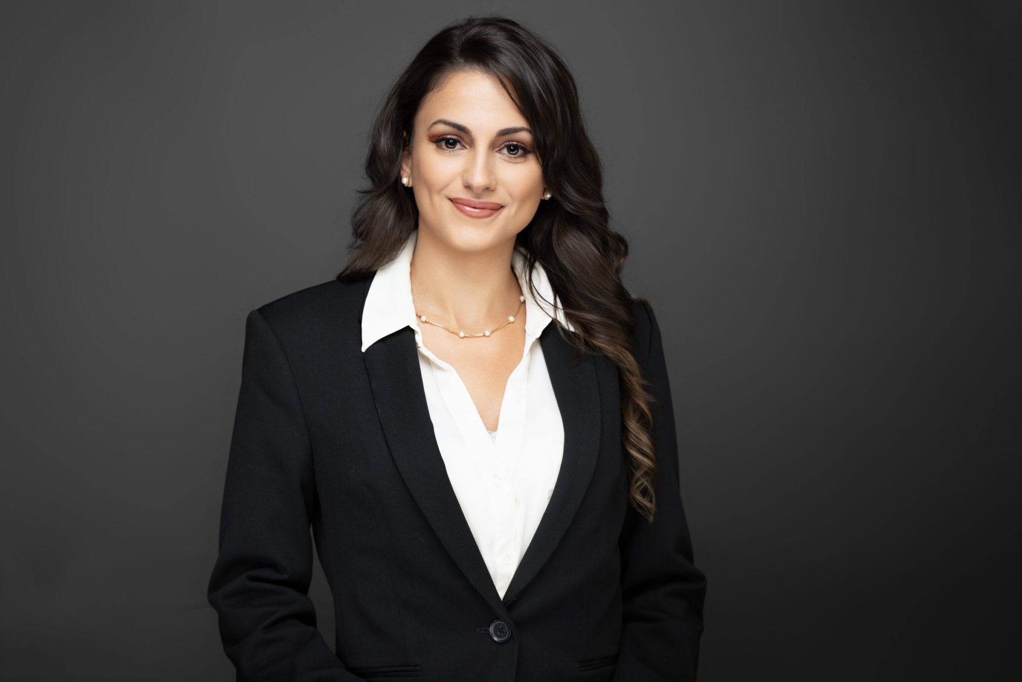 Professional woman in a black blazer and white shirt smiling confidently.