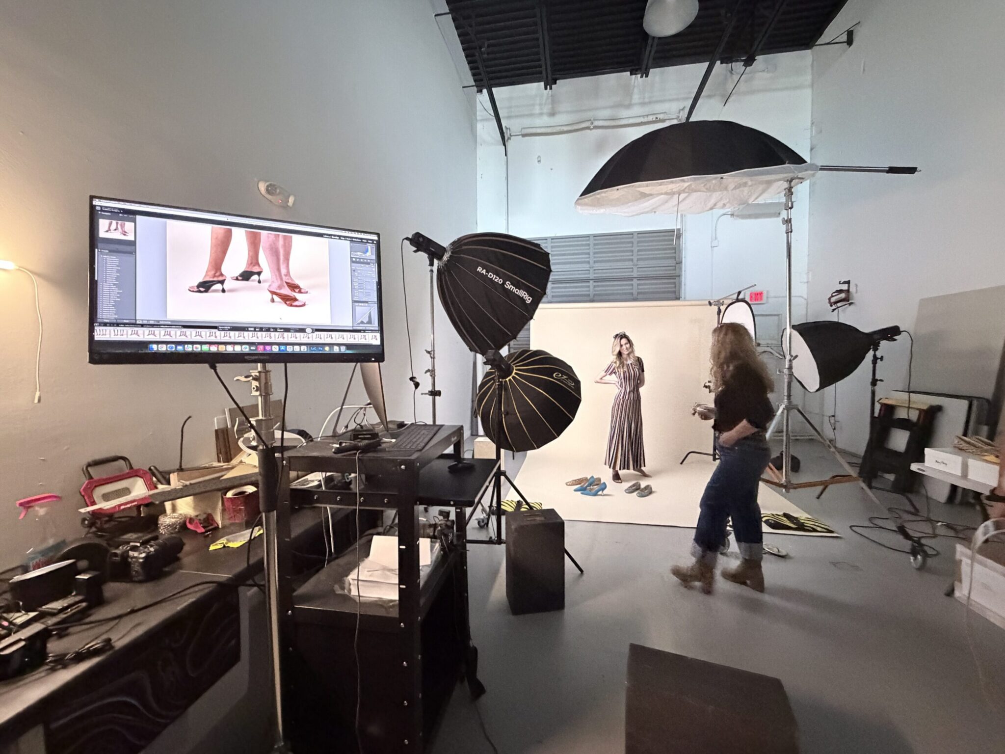 Photographer captures model in a professional studio setting with lighting equipment.
