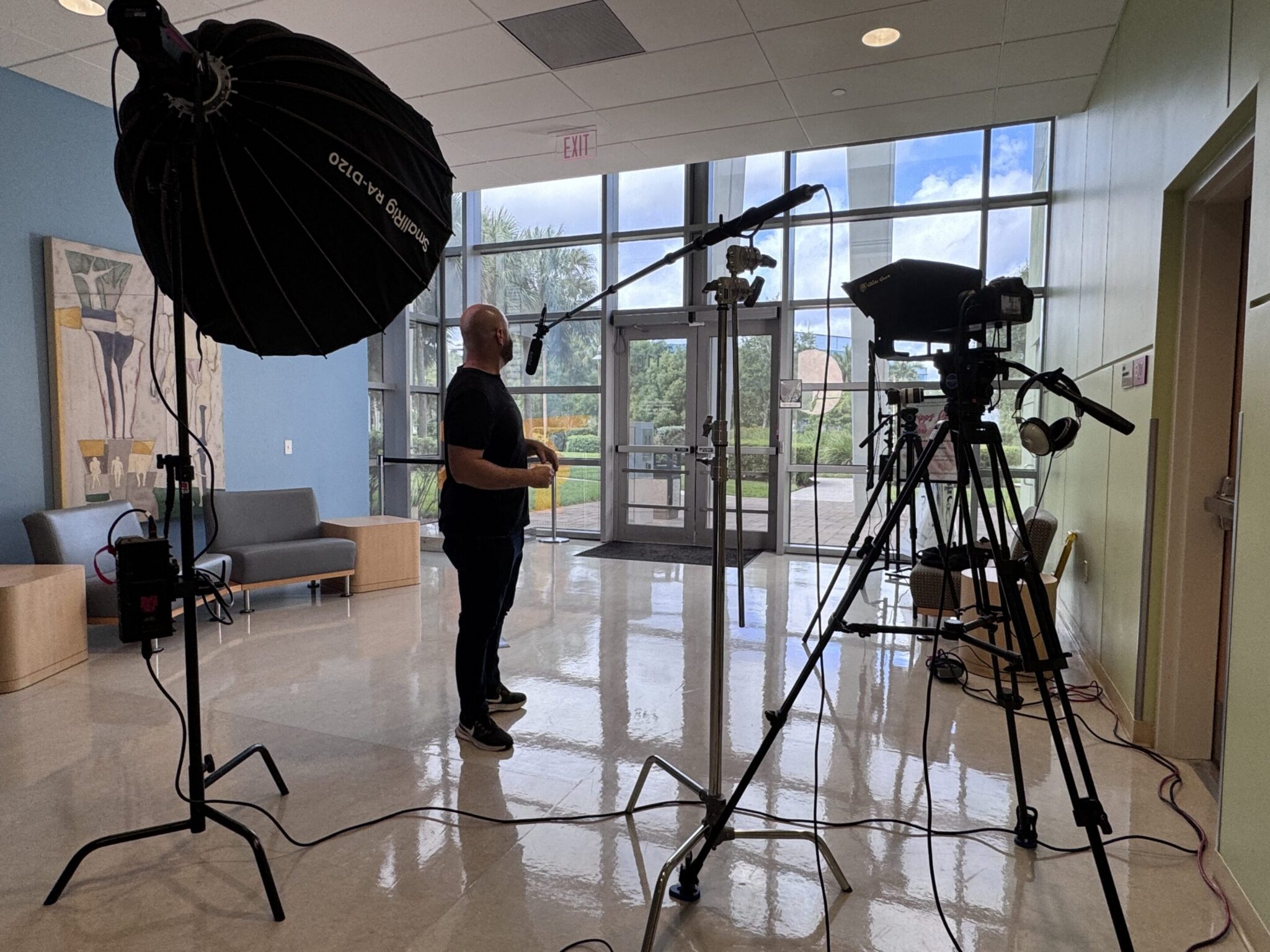 Man preparing for a video shoot in a bright studio with large windows.