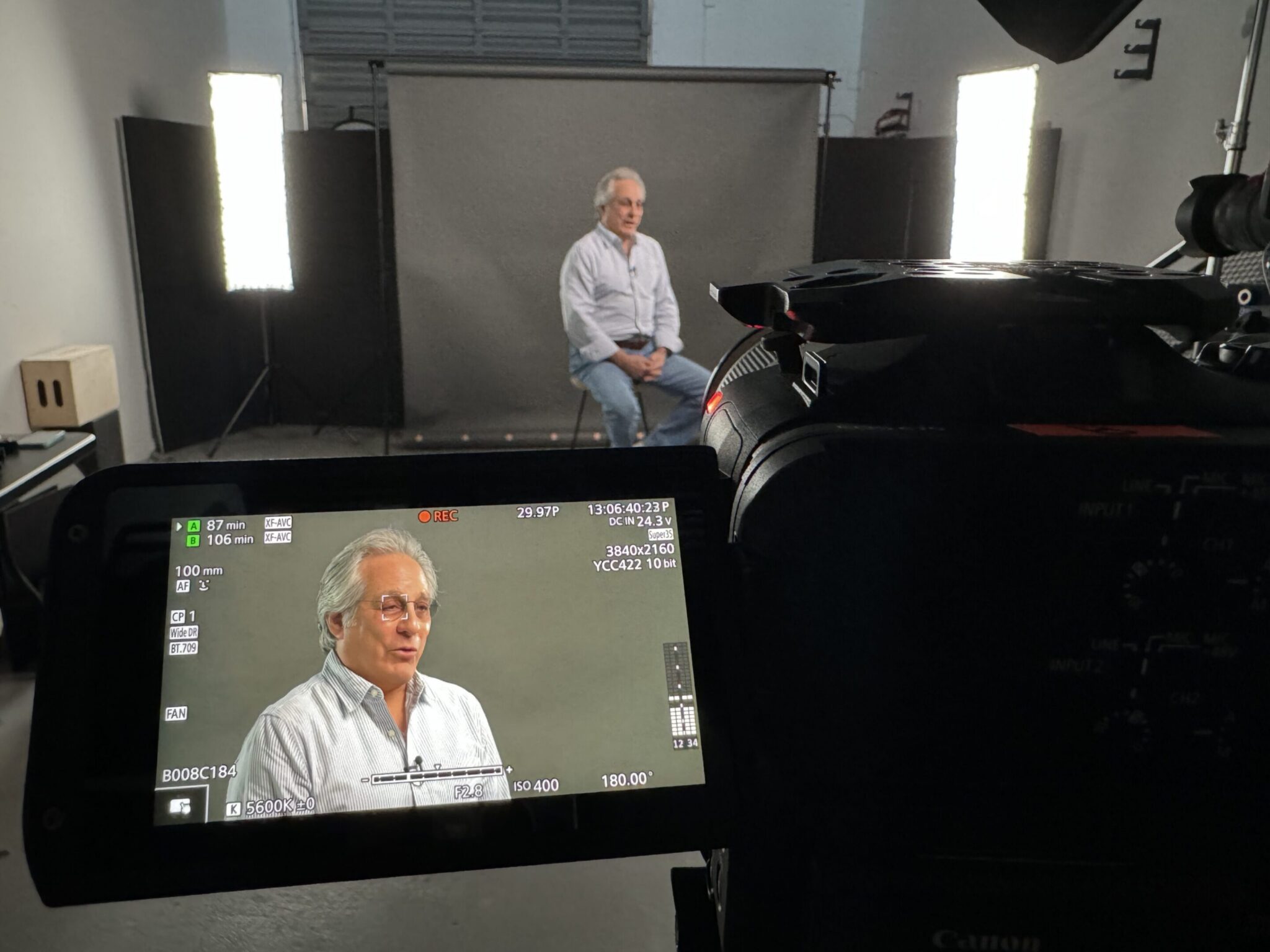 An elderly man being interviewed in a studio with professional lighting.