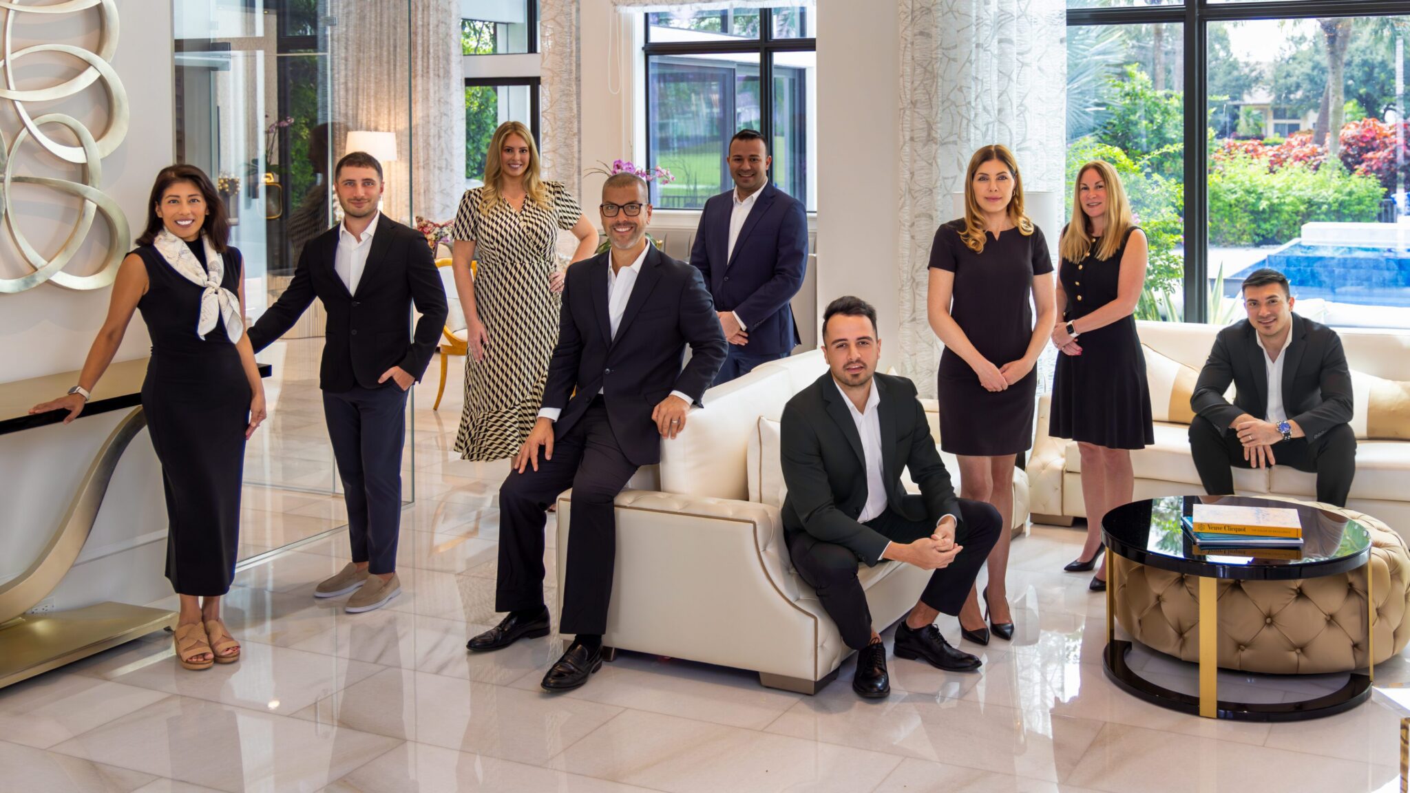 A professional group photo of seven well-dressed businesspeople in a modern office.