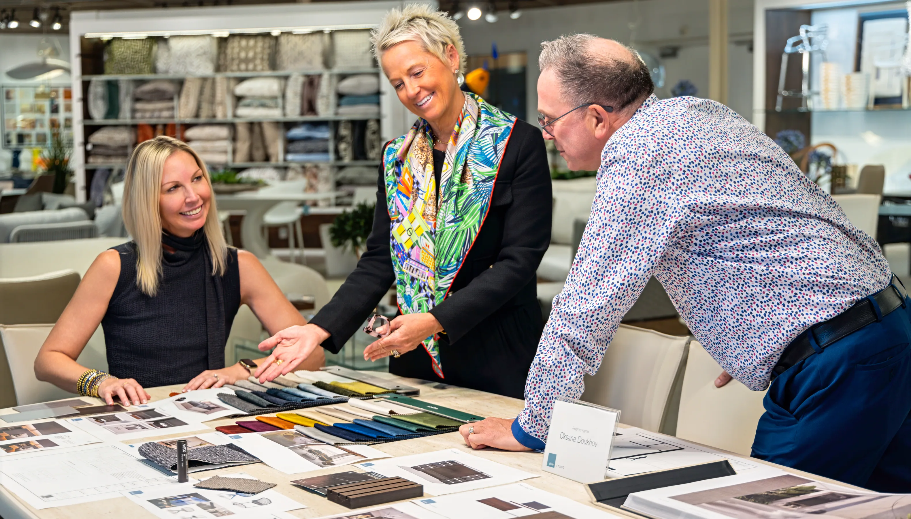 Three people discussing fabric samples at a table.